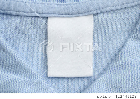 White blank laundry care clothes label on blue shirt fabric background White blank laundry care clothes label on blue shirt fabric background 112441128