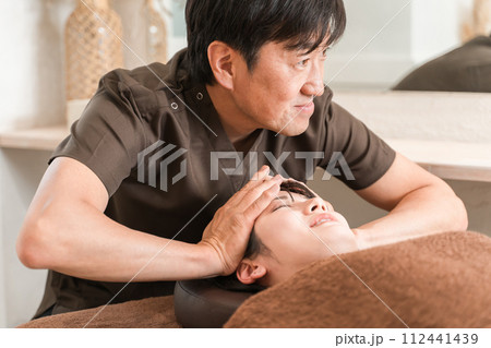 ヘッドマッサージ・ヘッドスパ・頭皮マッサージ・スカルプケア・小顔矯正をする女性と整体師・セラピスト ヘッドマッサージ・ヘッドスパ・頭皮マッサージ・スカルプケア・小顔矯正をする女性と整体師・セラピスト 112441439