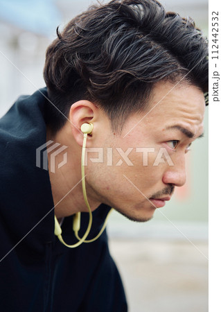イヤホンで音楽を聴く男性 112442532