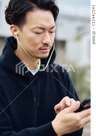 イヤホンで音楽を聴く男性 112442541