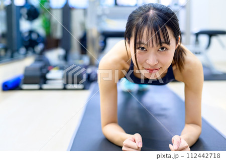 パーソナルジムで体を鍛える若い女性　筋トレ女子　腕立て伏せ　プランク　正面 112442718