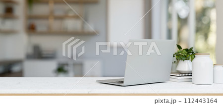 A back view image of a laptop computer and decor on a white table in a modern and clean office. 112443164