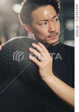 トレーニングジムで真剣な表情で腹筋をするストイックな若い男性 112443394