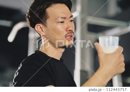 トレーニングジムでプロテインを飲む若い男性 トレーニングジムでプロテインを飲む若い男性 112443757