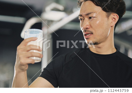 トレーニングジムでプロテインを飲む若い男性 トレーニングジムでプロテインを飲む若い男性 112443759