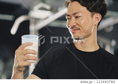 トレーニングジムでプロテインを飲む若い男性 112443760