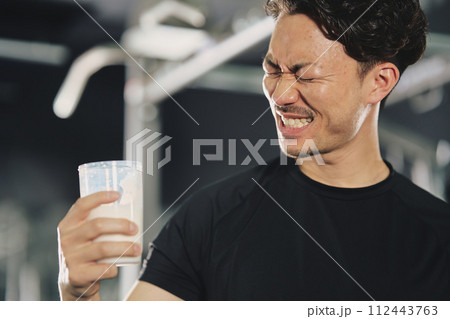 トレーニングジムでプロテインを飲む若い男性 112443763