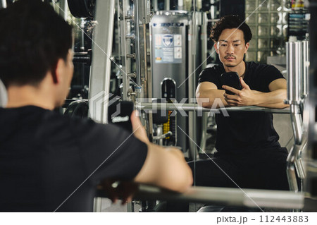 トレーニングジムで携帯アプリを使う男性 トレーニングジムで携帯アプリを使う男性 112443883