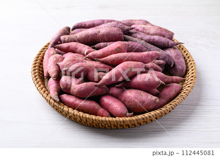 Organic raw sweet potatoes in basket on white table 112445081