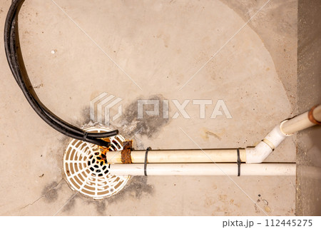Selective focus on a residential house basement floor drain with furnace and water softener drain lines 112445275