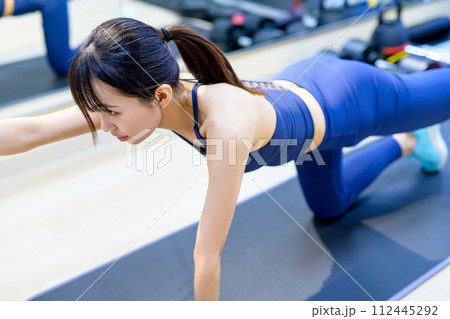 パーソナルジムで体を鍛える若い女性　筋トレ女子　腕立て伏せ　片手プランク　 112445292