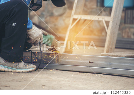 Construction Worker hands using Welding machinery iron metal sparking. Men hands wear protective glove Hot flame metal work cutting fire iron workshop. Locksmith use Welding machine cut metal process 112445320