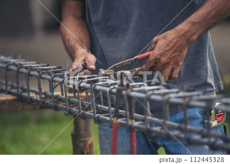 Construction Men hands bending cutting steel wire fences bar reinforcement of concrete work. Worker hands using pincer pliers iron wire. Outdoor Worker using wire bending pliers, construction work 112445328