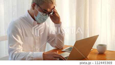 Asian Man thinking wear eyeglasses using laptop at home office. Desperate man stress headache depressed from startup small business at home office. Failure businesman working holding smart tablet 112445369