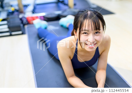 パーソナルジムで体を鍛える笑顔の若い女性　筋トレ女子　腕立て伏せ　プランク　ストレッチ　ヨガ 112445554
