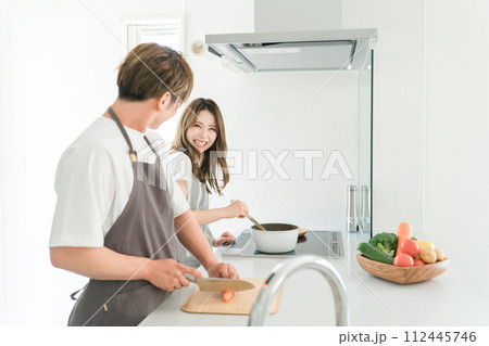 家のキッチンで一緒に料理を作る若いアジア人夫婦 112445746