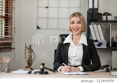 Beautiful Asian woman Lawyer Or Judge working at her office with court hammer and book on the table Legal And Justice. 112445970