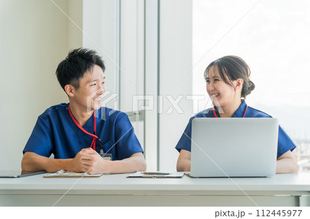 病院の会議室で笑顔で会話する医者・看護師・医療従事者の若いアジア人男女 112445977