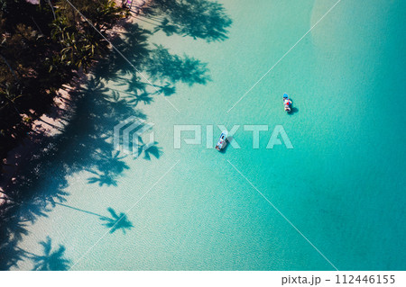 Beach with clear blue sea and palm tree shadows Beach with clear blue sea and palm tree shadows 112446155