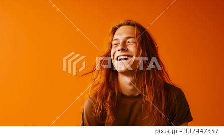 Handsome young male guy smile Asian with long red hair, on yellow orange background, banner, copy space, portrait. 112447357