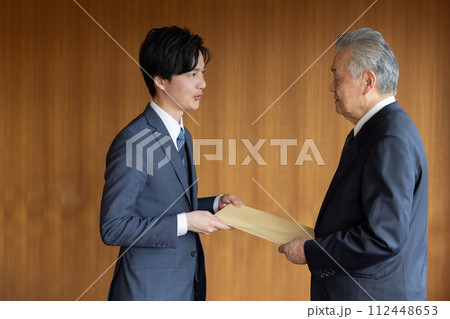 社外秘の封筒を渡すビジネスマン 社外秘の封筒を渡すビジネスマン 112448653