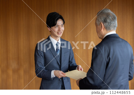 社外秘の封筒を渡すビジネスマン 112448655