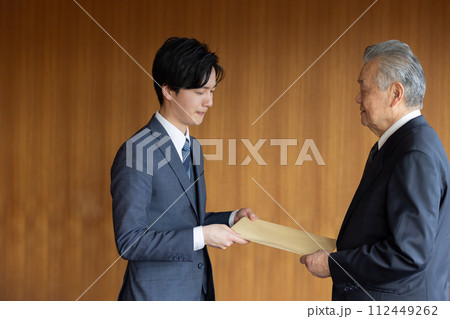 社外秘の封筒を渡すビジネスマン 社外秘の封筒を渡すビジネスマン 112449262