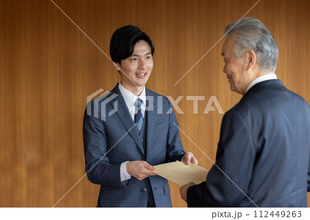 社外秘の封筒を渡すビジネスマン 社外秘の封筒を渡すビジネスマン 112449263