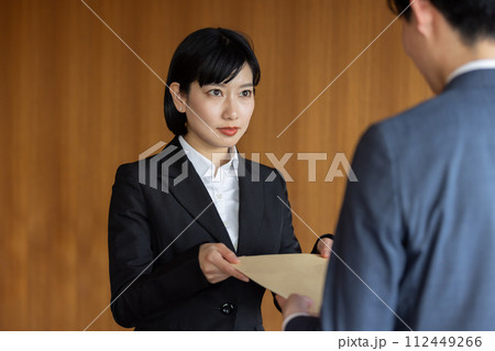 社外秘の封筒を渡すビジネスウーマン 112449266