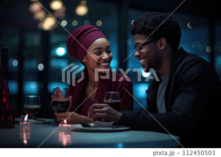 Amidst a warm restaurant ambiance, a happy couple in love shares smiles and laughter, their connection evident in the joyous atmosphere of shared moment and romantic bliss 112450503