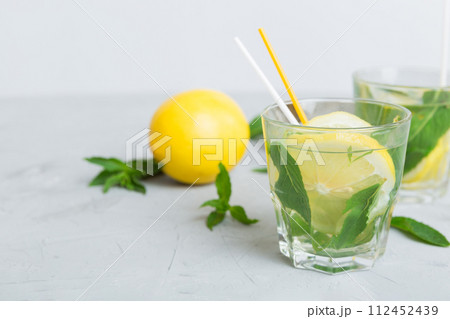 Mojito cocktail. Refreshing mojito cocktail with lime, lemon and mint in a tall glass with a stick Mojito cocktail. Refreshing mojito cocktail with lime, lemon and mint in a tall glass with a stick 112452439