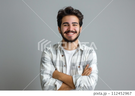 A man with a beard and a white shirt is smiling and crossing his arms 112452967