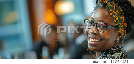 A woman with glasses and a colorful head scarf is smiling 112453243