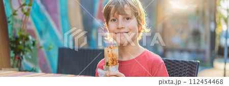 Boy eating street food in Istanbul. Balik ekmek - fish in a bread, traditional Turkish fast food. Istanbul, Turkey BANNER, LONG FORMAT 112454468
