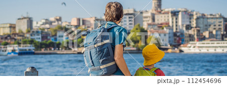 Father and son tourists enjoy Istanbul city skyline in Turkey, Beyoglu district old houses with Galata tower on top, view from the Golden Horn BANNER, LONG FORMAT 112454696