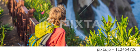 BANNER, LONG FORMAT Boy tourist with a backpack on the background of Duden waterfall in Antalya. Famous places of Turkey. Lower Duden Falls drop off a rocky cliff falling from about 40 m into the 112454720