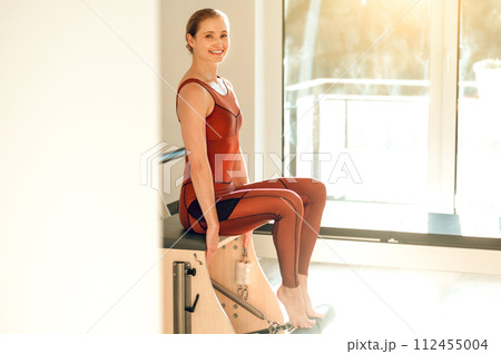 Attractive slim woman training her sporty body on the Pilates machine 112455004