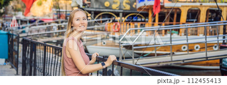 Woman tourist in Old town Kaleici in Antalya. Turkiye. Panoramic view of Antalya Old Town port, Taurus mountains and Mediterrranean Sea, Turkey BANNER, LONG FORMAT 112455413