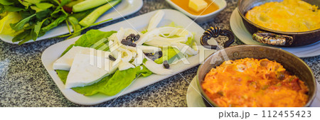 BANNER, LONG FORMAT Turkish breakfast table. Pastries, vegetables, greens, olives, cheeses, fried eggs, spices, jams, honey, tea in copper pot and tulip glasses, wide composition BANNER, LONG FORMAT Turkish breakfast table. Pastries, vegetables, greens, olives, cheeses, fried eggs, spices, jams, honey, tea in copper pot and tulip glasses, wide composition 112455423