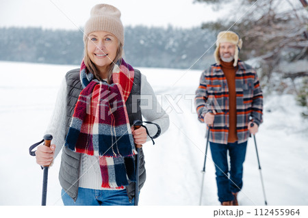 Happy mature couple with scandinavian stick on a walk in a forest 112455964