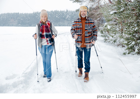 Couple on a walk with scandinavian sticks 112455997