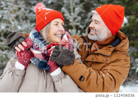 Mature couple looking close and romantic while spending time in a winter park Mature couple looking close and romantic while spending time in a winter park 112456036