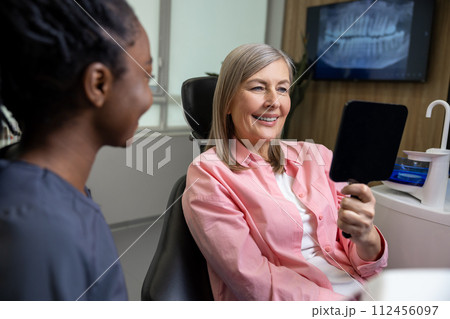 Caucasian lady checking her beautiful smile in mirror after stomatology treatment 112456097
