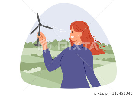 Wind turbine in hands of woman with smile standing in nature, and developing alternative energy Wind turbine in hands of woman with smile standing in nature, and developing alternative energy 112456340