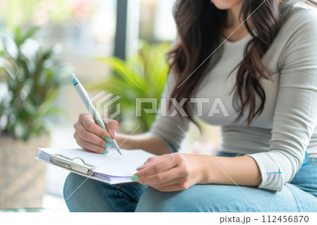 Woman brainstorming ideas with a notepad and pen. Hand with pen writing on notebook. Generative AI 112456870