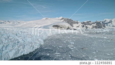 Antarctica glacier ocean shore landscape aerial. Melting snow covered glacier at winter sunny day. Environment concept of global warming. Nobody nature of South Pole. Shot of climate change 112456891