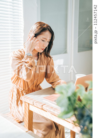 髪を耳にかけるリモートワーク中の女性 112457142