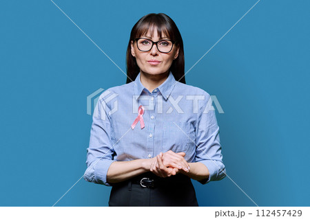 Middle-aged woman with pink ribbon symbolizing International Breast Cancer Day 112457429