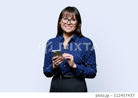 Business mature woman holding smartphone on white background Business mature woman holding smartphone on white background 112457437
