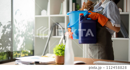 Young woman cleaning to disinfect the office office cleaning staff cleaning maid. Female cleaner holding a bucket with cleaning supplies Young woman cleaning to disinfect the office office cleaning staff cleaning maid. Female cleaner holding a bucket with cleaning supplies 112458828